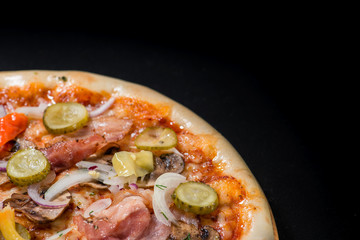 closeup Tasty pizza with mushrooms, ham and pickles on a black b
