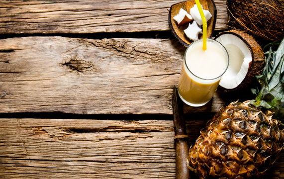 Fresh cocktail with coconut, rum and pineapple on a wooden table. Free space for text.