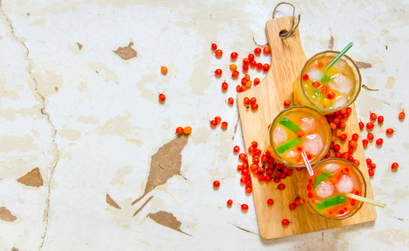 Three cocktails from sea-buckthorn berries , ice and lime on the old table . Free space for text.