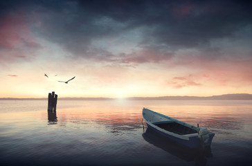 Canoe floating on the calm water under amazing sunset