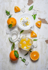 Fresh orange juice with ice, with slices of oranges and a juicer.