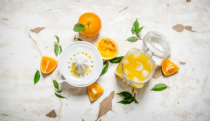 Fresh orange juice with ice, with slices of oranges and a juicer.