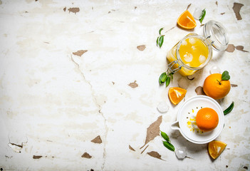 Fresh orange juice with ice, with slices of oranges and a juicer.