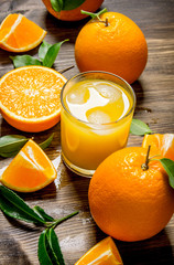 Fresh juice in glass and oranges slices with leaves.