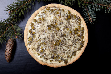 Pie with filling with Christmas tree branches on a black backgro