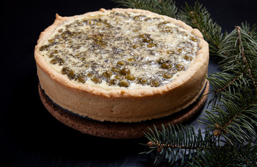 Pie with filling with Christmas tree branches on a black backgro