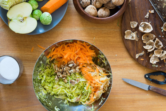 Carrot, savoy cabbage, brussels sprouts, apple and walnuts in a metal bowl