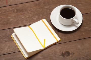 White cup of coffee and notebook on old wooden table