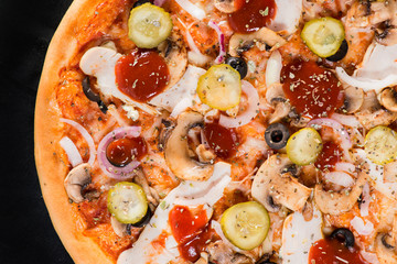 closeup Tasty pizza with mushrooms, ham and pickles on a black b