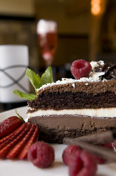 Layered chocolate cake slice dessert with fresh strawberries, raspberries and mint.