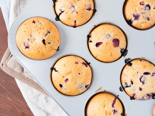 Just baked yogurt muffins with blackberries, blueberries and raspberries in a muffin tin on wooden...