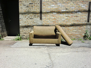 Lonely abandoned brown couch in an alley