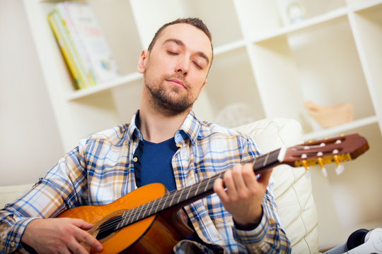 Portrait of a young man playing the guitar at home
