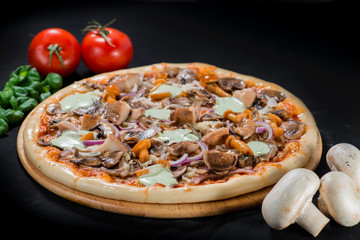 closeup Tasty pizza with mushrooms, ham and pickles on a black b