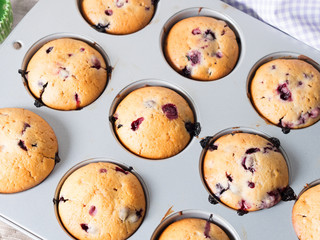 Just baked muffins with wild berries - blackberrries, blueberries and raspberies in a muffin tin, top angle view closeup