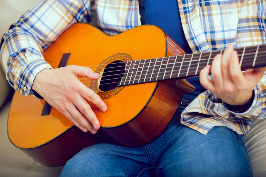 Portrait of a young man playing the guitar at home