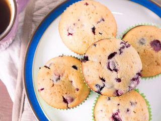 Wild berries muffins with paper cases on plate, top view closeup