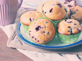 Home made muffins with blackberries and blueberries on brown wooden table with table napkins, closeup, toned
