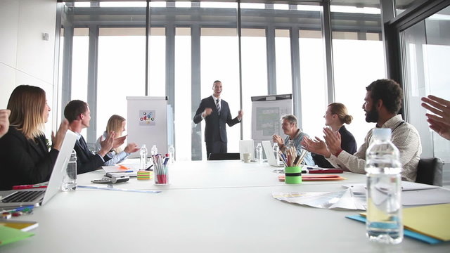 Colleagues applauding smiling businessmen during a meeting 