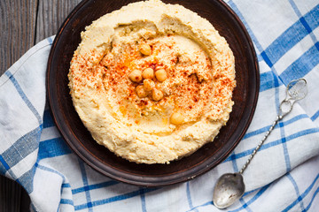 A bowl of creamy hummus with olive oil, paprika and pita chips