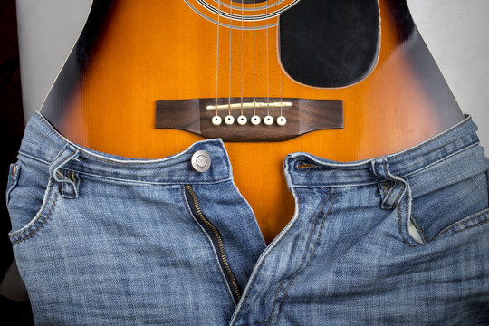 Blue jeans put on an acoustic guitar, which is similar to the curves of the female body in the area of the hips