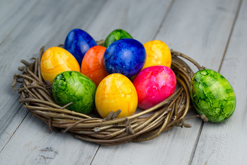 Nest with colored easter eggs on a wooden background