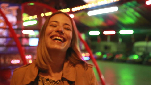 Portrait of woman looking at camera and laughing in amusement park