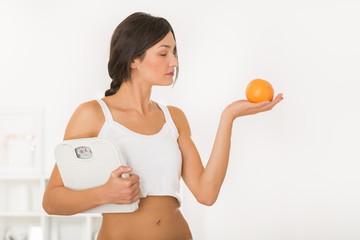 Young girl holding a measuring scale and an orange