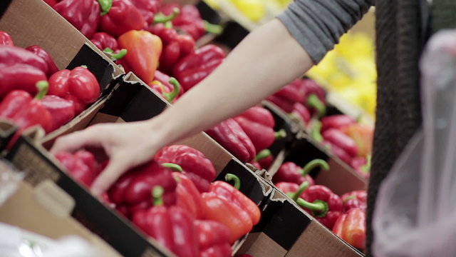 Young woman chooses paprika on store shelves.
