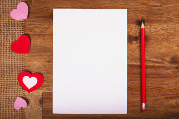 Valentines day white paper with red hearts and pen on wooden table