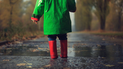 Baby walking in autumn rainy park