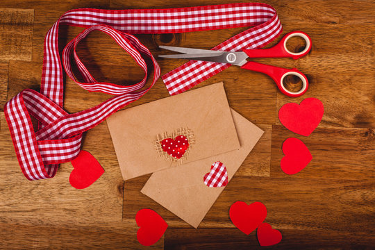 Hearts, envelopes, scissors, ribbons on wood background. Handmade valentines day decoration