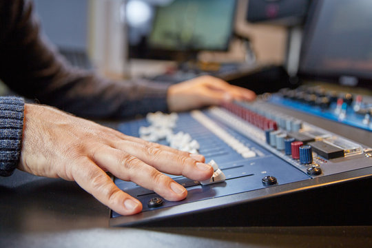 Hands of a man on adjusting a production console