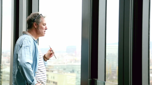 Profile of creative director standing by window, smoking electronic cigarette