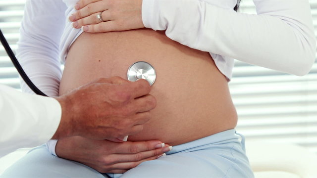 Pregnant smiling woman consulting doctor