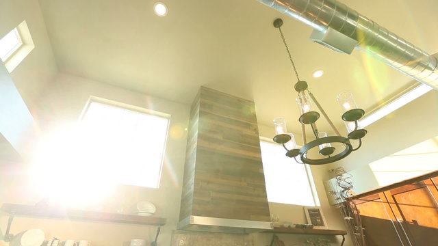 Tilt Down From Ceiling to Reveal Kitchen and Dining Room. camera tilts down with sun flare from window to reveal modern industrial style kitchen and dining room combination
