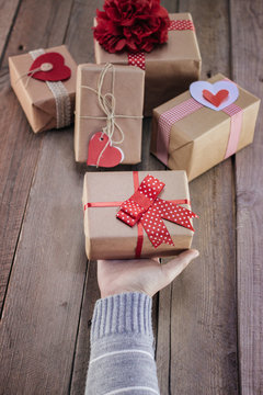 Female hands holding gift on wooden table