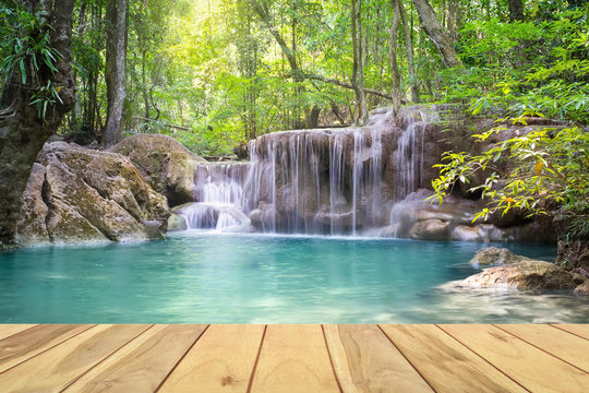 Waterfall, green forest in Erawan National Park in Thailand montage with wooden floor. Landscape with water flow, tree, river, stream and rock at outdoor. Beautiful scenery of nature for vacation. © DifferR