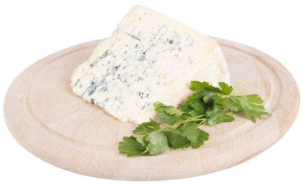 Slice of tasty blue cheese and parsley on cutting board