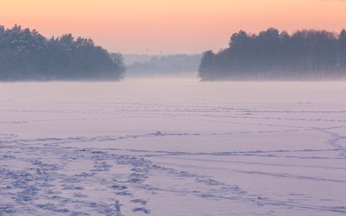 Sunset sky over frozen and snowy lake.