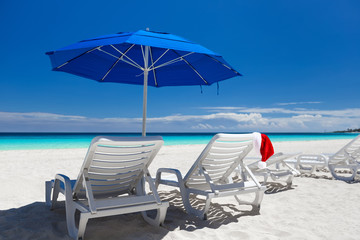 Caribbean beach with blue sun umbrellas and white sunbeds