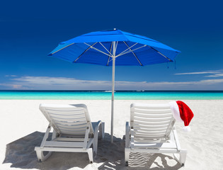 Caribbean beach with blue sun umbrellas and white sunbeds