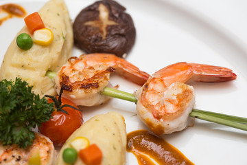A steak shrimp with  fresh with fresh vegetables on a white plat