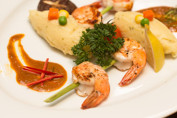 A steak shrimp with  fresh with fresh vegetables on a white plat