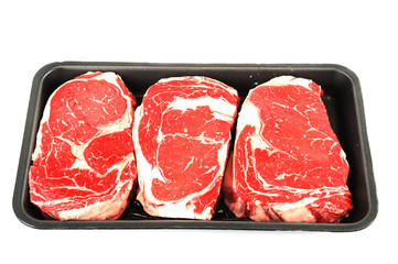 fresh raw rib eye steak in container tray