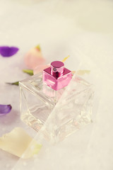 Bottle of perfume and rose petals on fabric background