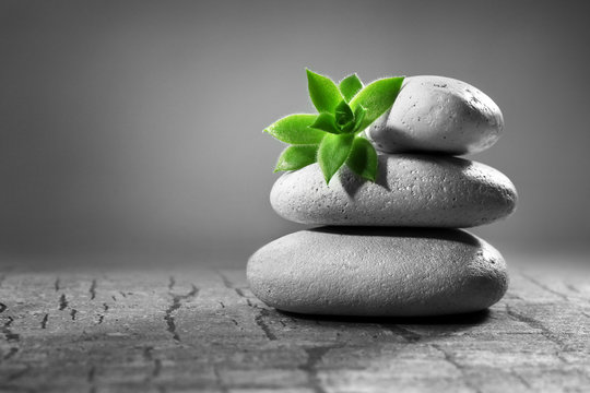 Pile of pebbles with leaf on the table against grey background