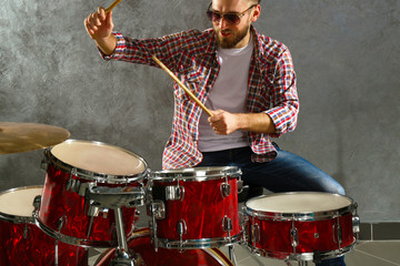 Fototapeta na wymiar Musician playing the drums on grey wall background