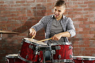 Fototapeta na wymiar Musician playing the drums on brick wall background