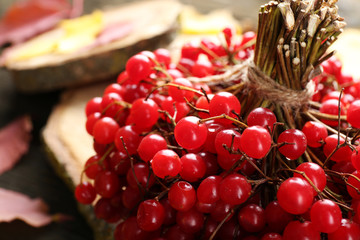 Autumn composition: bunch of viburnum and colourful leaves on wooden table, close up